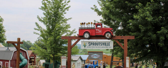 Sproutsville entrance sign with red truck and sunflowers, Cherry Crest Adventure Farm attraction.